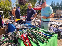Customers looking over bike parts (forks in foreground) at Bicycle Exchange Sep 2023 parking lot swap meet