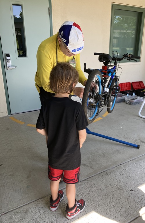 Child watches as adult adjusts child's bike on a repair stand